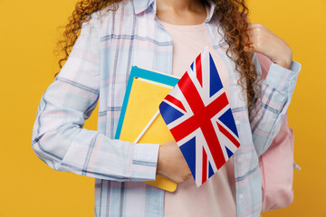 Cropped close up young black teen girl student she wearing blue casual clothes backpack bag hold books british flag isolated on plain yellow color background. High school university college concept.