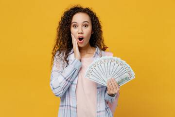 Young shocked fun black teen girl student she wear casual clothes backpack bag hold fan cash money in dollar banknotes isolated on plain yellow color background High school university college concept