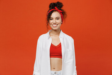 Young trendy smiling happy fun fashionable woman of African American ethnicity 20s she wearing white shirt red top headscarf looking camera isolated on plain orange color background studio portrait.