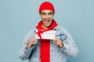 Young happy middle eastern man 20s he wear denim jacket red hat hold gift certificate coupon...
