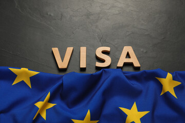 Word Visa made of wooden letters and European Union flag on black table, flat lay