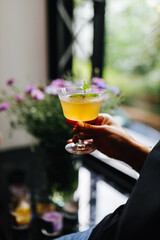 alcoholic cocktail in hand on the background of the window
