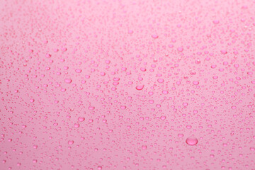 Water drops on pink background, closeup view