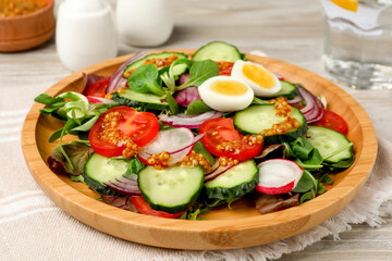 Tasty salad with vegetables and quail eggs on wooden table, closeup
