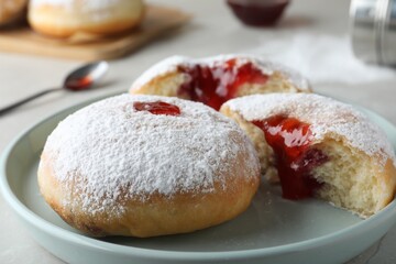 Delicious donuts with jelly and powdered sugar on plate, closeup