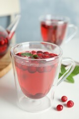 Tasty hot cranberry tea with mint and fresh berries on light table