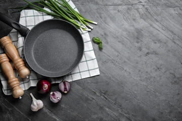 Flat lay composition with frying pan and fresh products on grey table, space for text