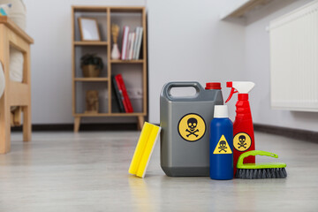 Bottles of toxic household chemicals with warning signs, brush and scouring sponge in room, space for text - obrazy, fototapety, plakaty