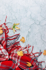 Red and gray autumn flat lay composition. Plaid and autumn leaves on gray marble background.