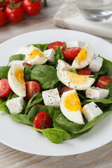 Delicious salad with boiled eggs, feta cheese and tomatoes on table, closeup