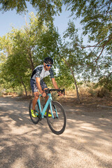 Cyclist pedaling his racing bike outdoors with all his safety equipment: helmet, sunglasses, on a sunny day