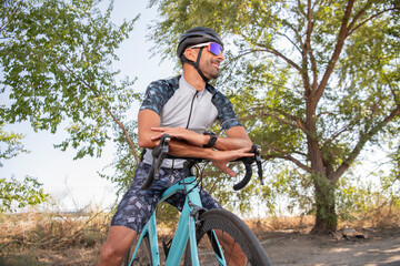 Obraz premium Triathlon athlete leaning on the handlebars smiling with helmet and sunglasses. Security
