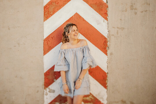 Happy woman laughing against shabby wall