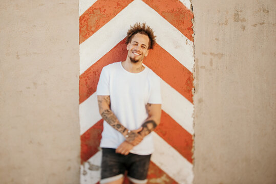 Cheerful ethnic guy standing near wall