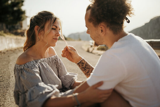 Happy young couple enjoying each other while sitting on road and embracing