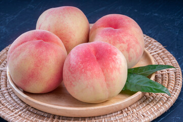 Peach fruit with leaf on black background, Fresh Peach on wooden plate over black wooden Background.