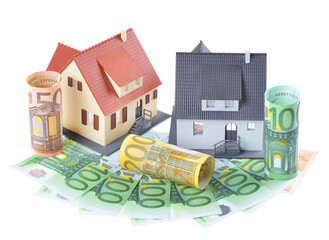 Miniature model of houses on stacked euro banknotes, on isolated white background. Real estate investment concept. Saving money for future retirement.