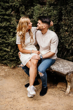 Happy couple sitting on bench and holding hands while having dat