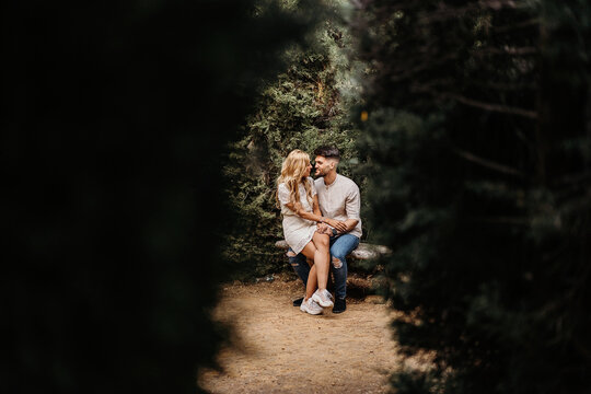 Happy couple sitting on bench and holding hands while having dat