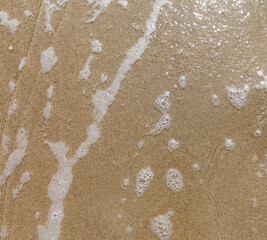 Sandy beach wet surface, top view. Sea tide waves, natural sand and water texture. Smooth sand background.