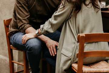 Fototapeta premium A couple in love is sitting in front of each other and touching the others leg. Connecting while talking. Physical contact, gentle touch. Romantic date moment.