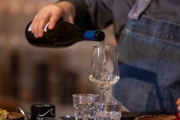 Weißwein wird in ein Glas geschüttet