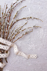 Fototapeta na wymiar willow branches and cotton ribbon on grey background,