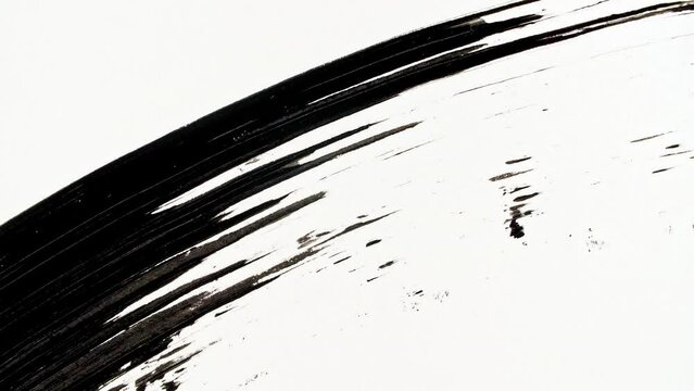 Macro shot and slow motion of a black mascara isolated on white background. Professional makeup. Closeup of a mascara wand on white background. High quality 4k footage