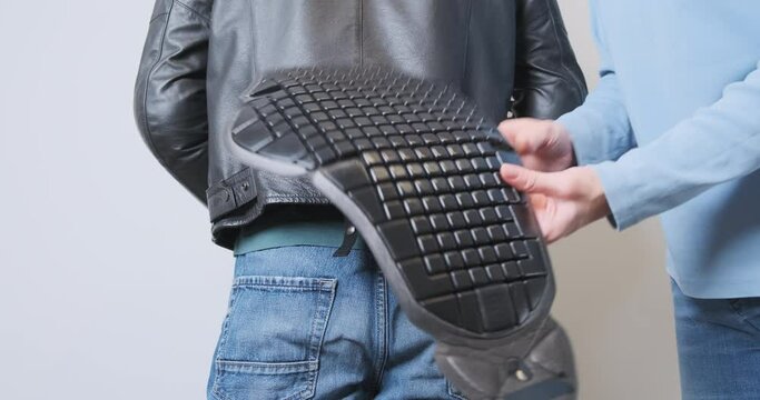 Woman tucks a plastic back protector into a standing biker's leather motorcycle jacket. Back view. The concept of road safety, moto protection, preparation for the trip.