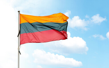 Naklejka na ściany i meble Large Lithuanian national flag on flagpole waving in wind against blue cloudy sky