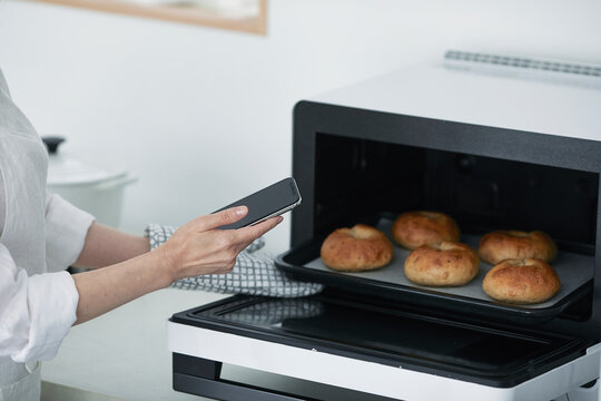 女性の手と電子レンジとスマートフォン