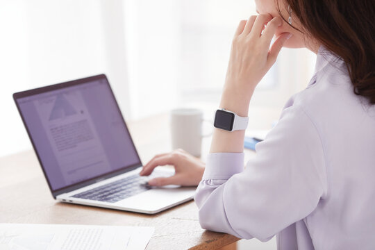 スマートウォッチとノートパソコンと女性の手