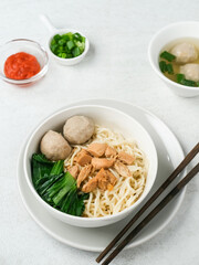 Mie ayam or bakmi ayam is a common Indonesian dish of seasoned yellow wheat noodles topped with diced chicken. Served in a white bowl.