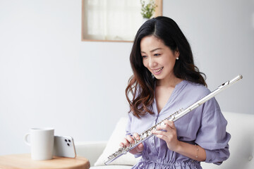スマートフォンを見ながらフルートを持つ女性