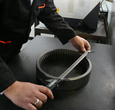 person measuring metal in factory