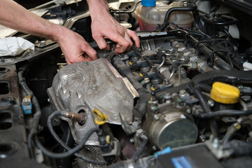 Car mechanic hands replacing a camshaft position sensor. Mechanics workshop.