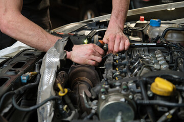 Fototapeta na wymiar Close up of car mechanic hands doing car service and maintenance. Mechanics workshop.