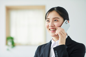 スマートフォンを持ち喜ぶスーツを着た若い女性