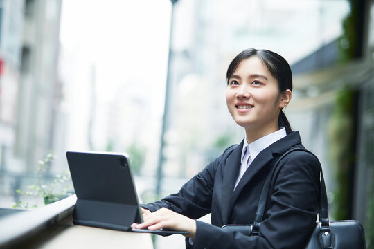 スーツを着てタブレット端末を操作する若い女性