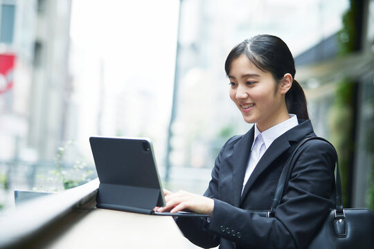 スーツを着てタブレット端末を操作する若い女性