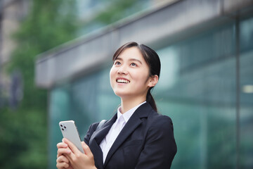 スマートフォンを持つスーツを着た笑顔の若い女性