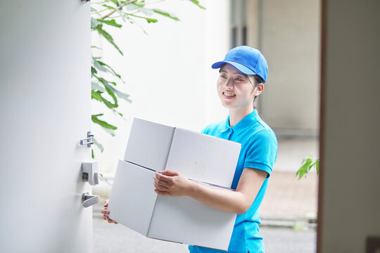 作業服を着て笑顔で荷物を運ぶ若い女性