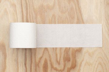 a roll of toilet paper on a wooden background is unwound with a place for an inscription or text...