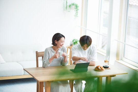 リビングでタブレットPCを見る若い女性と男性