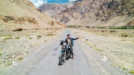 man traveling on motorcycle through Spiti Valley in Himachal Pradesh of India with extreme Himalayan Mountain landscape