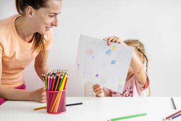 Child girl shows a drawn drawing with colored pencils on paper
