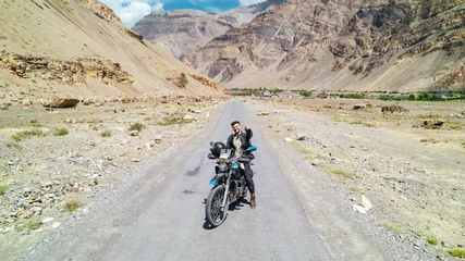 Photo sur Plexiglas Himalaya happy guy on motorcycle on desolate dry mountain road in desert of Spiti Valley Himachal Pradesh