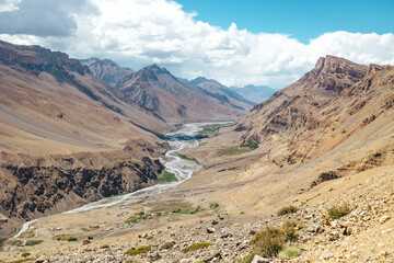 Fototapeta na wymiar sunny dry desolate mountain landscape in Spiti Valley with river flowing in summer