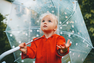 Child with umbrella wonders rainy weather walking outdoor toddler girl wearing red raincoat autumn season september