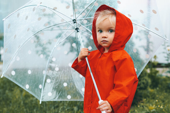 Autumn season child with umbrella walking outdoor wearing red raincoat rainy weather 2 years old kid